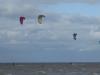 Kitesurfers genieten van de straffe wind, de ruwe zee en het fletse zonnetje